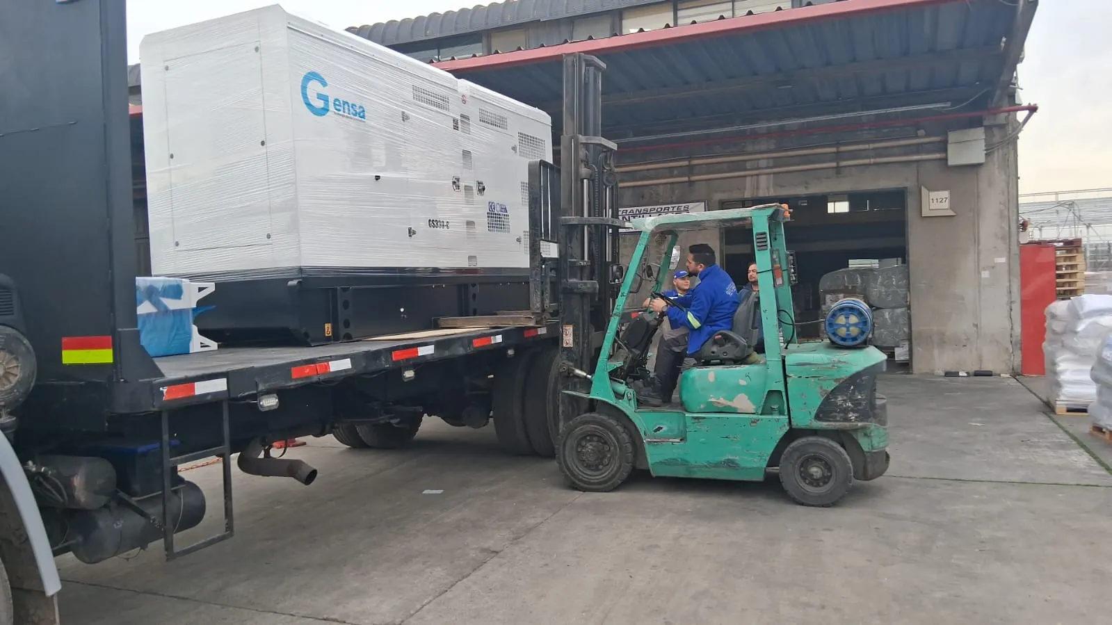 Grúa horquilla cargando un generador sobre camión plano
