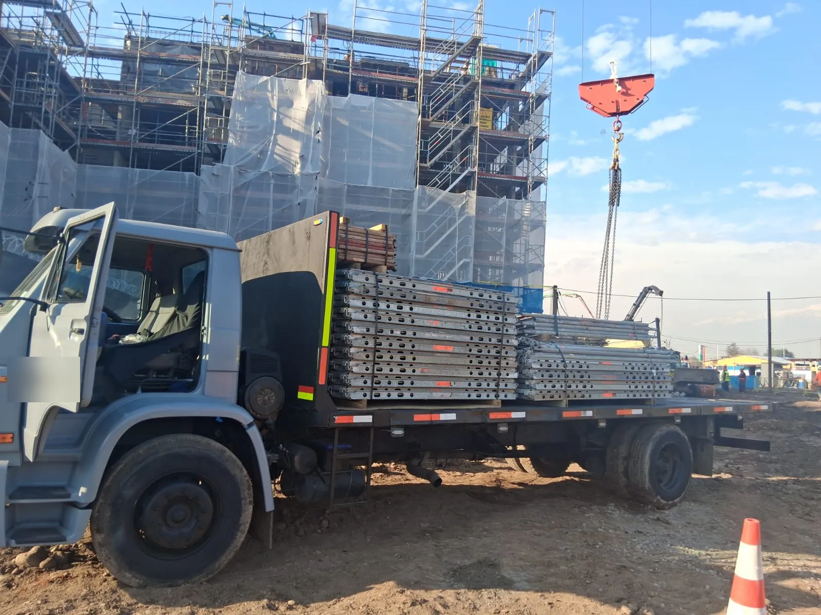 Camión plano de TRANS ISIDORA SPA cargado con estructura metálica en una obra en Santiago
